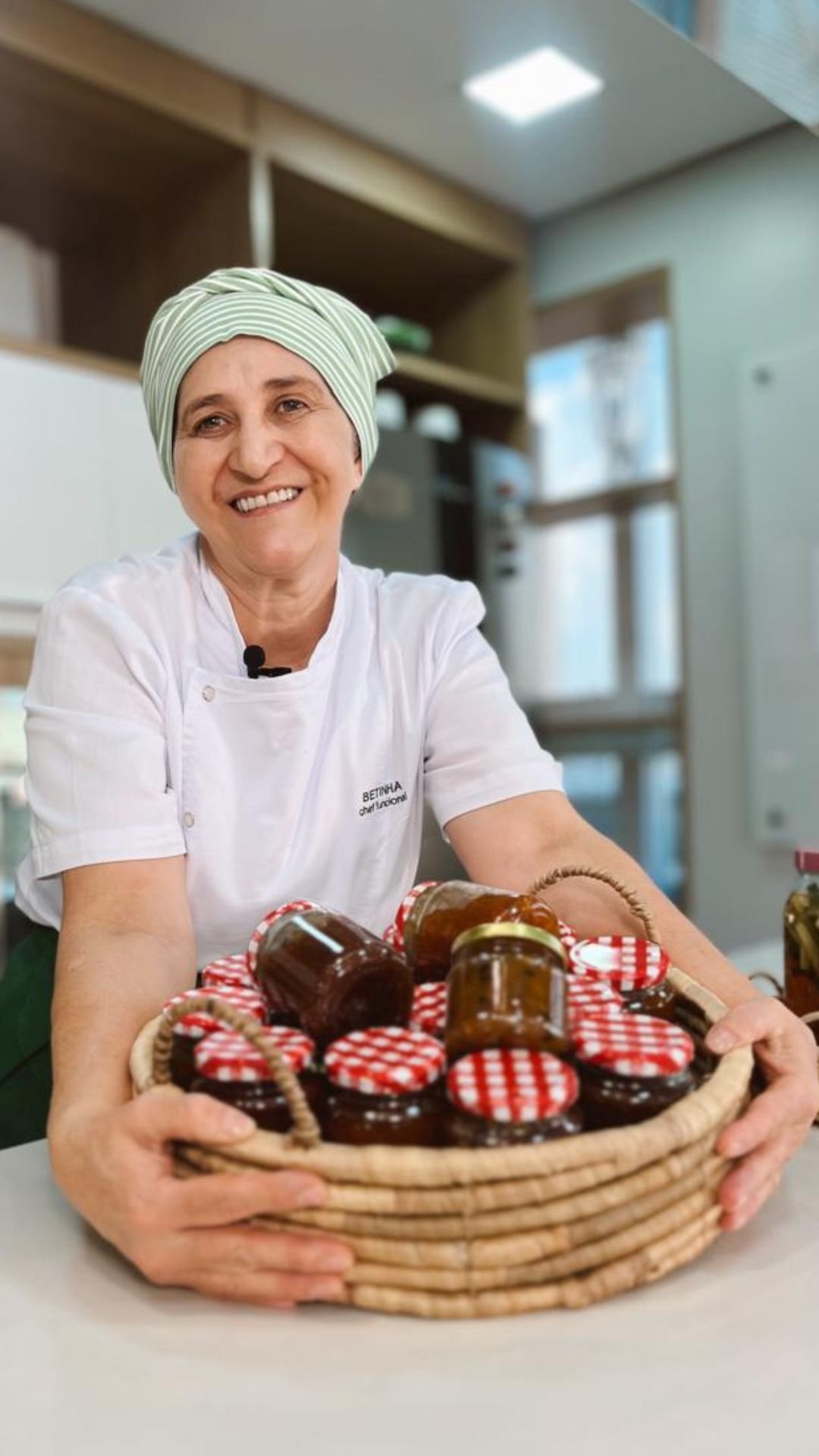 Dona Betinha na cozinha da escola, com uma cesta de geleias